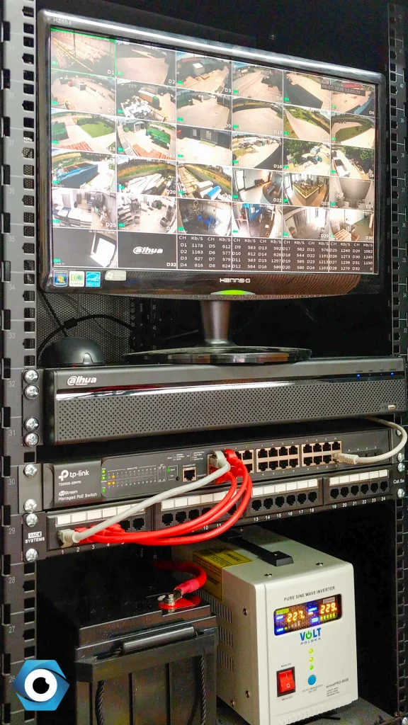 Otwarta szafa RACK z rejestratorem, monitorem podglądowym i zasilaczem awaryjnym UPS w firmowej serwerowni.
