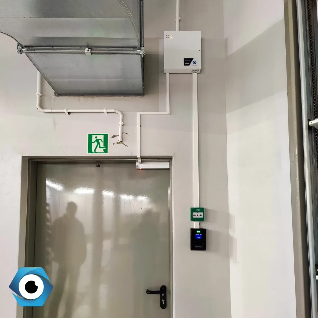 Bezpieczne drzwi z czytnikiem KD oraz widoczną natynkową instalacją sterownika w strefie o podwyższonym rygorze.
